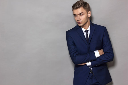 Portrait of an elegant handsome businessman, wearing a blue classic suit and white shirt, on a gray background with copy space.の写真素材