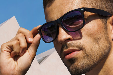 Unshaven man in sunglasses on the background of white architecture, sunglasses advertisement.の写真素材