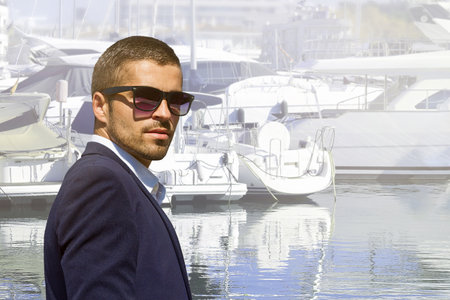 A man in sunglasses on the background of yachts on a summer vacation, hot sun.の写真素材
