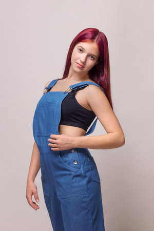 A girl in a blue denim overalls poses in the studio, a three-quarter portrait, advertising casual style.の写真素材