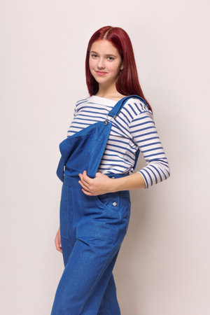 girl in a blue denim overalls and a striped blouse on a white isolated background. Summer, sea theme.の写真素材