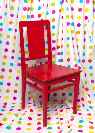 Red old chair against the backdrop of a curtain with colorful polka dots. vintage furniture.の写真素材