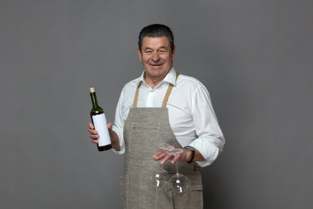 Mature man holding a bottle of red wine and two empty glassesの写真素材