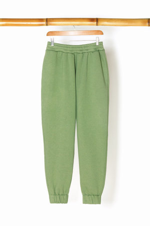 Sweatpants from a green sweatshirt hang on a wooden hanger. The concept of modern comfortable sportswear.の写真素材