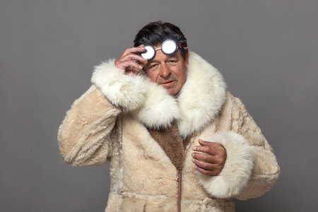 Mature man in a warm fur coat with a white fox collar and sunglasses. Demonstration of courage in cold frost conditions.の写真素材
