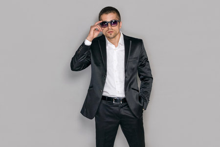 Handsome serious secret service agent in sunglasses over gray background, isolated. Professional man.の写真素材