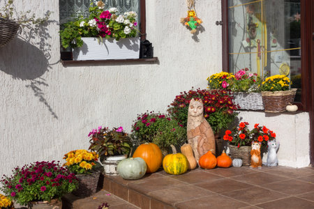 The porch of the house is decorated for Halloween with flowers and pumpkins, a sunny October day.の写真素材