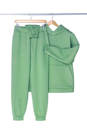 Green, menthol sports hoodie and pants hanging on a wooden hanger. Isolated on white background.の写真素材