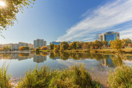 Autumn pond or part of river with reflection of sky and buildings. City lake in park in autumn.の写真素材