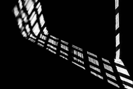 Abstract background, the shadow of a window frame cast on a dark surface. The strong contrast between light and shadow creates an abstract and spectacular geometric pattern.の写真素材