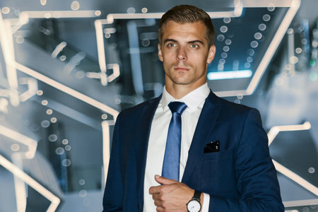 A male model in a dark blue suit, white shirt stands on a dynamic blue neon background. Professional manager, futuristic neon lighting.の写真素材