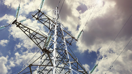 A metal pole supporting high-voltage power lines against a clear blue sky. The important role of...