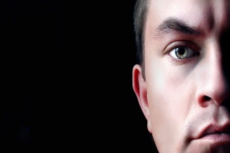 A dramatic portrait of a young man, isolated on black background. Half faceの写真素材