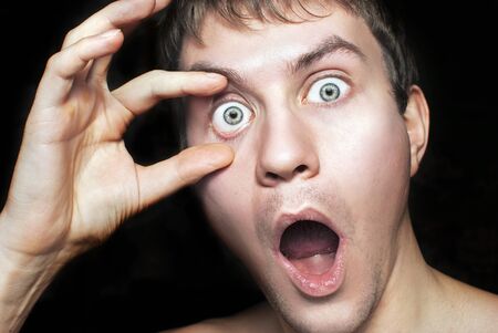 Portrait of a frightened or surprised guy close up. Isolated on a black backgroundの写真素材