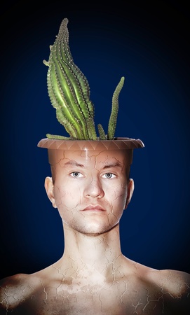 Portrait of young man with a pot on her head, which is growing cactus. The body is cracked. Background - projectors are not in focus.の写真素材