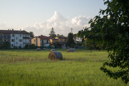 Countryside landscape with hay bales in the foreground and village in the backgroundの写真素材
