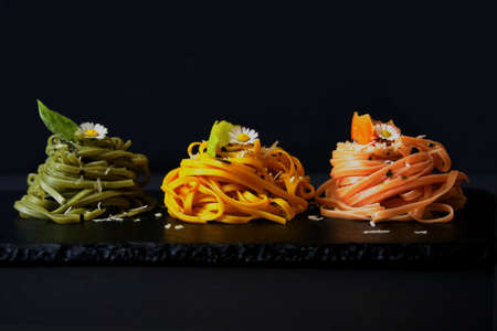 3 differently colored linguine nests arranged on a slate, horizontal, black backgroundの写真素材