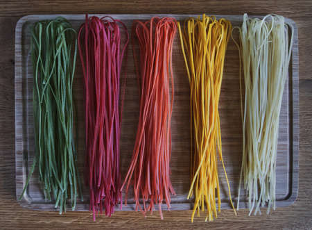 Colorful linguine raw in the gradient on a wooden board, horizontalの写真素材
