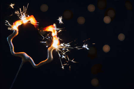 Burning clover-shaped sparkler, horizontal, black backgroundの写真素材