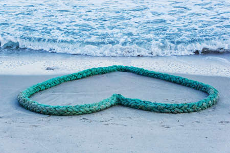 Green dew heart-shaped on the beach, horizontalの写真素材