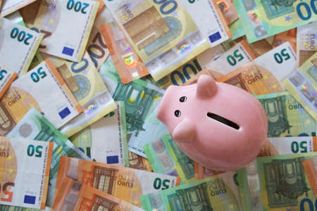 Pink piggy bank on a lot of bills, view from above, horizontalの写真素材