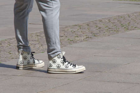 Unisex streetwear fashion shot with sneakers with the peace sign on them, landscape format, space on...