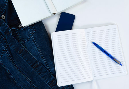 Opened white lined notebook with blue ballpoint pen on top, top view, white background, horizontal,...