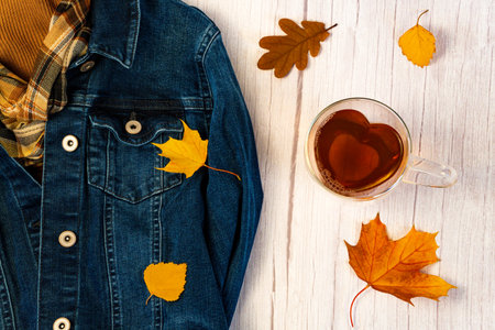 Heart-shaped glass tea cup on a light wooden background, top view, foliage, denim jacket, horizontalの写真素材