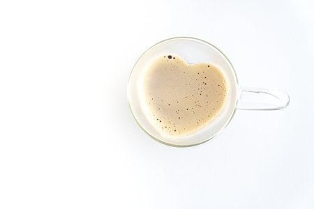 Heart shaped glass tea cup filled with coffee on white background, free space, isolated , top view,...