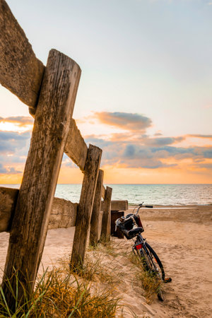 Bicycle and wooden fence on the beach at the blue hour before sunset, verticalの写真素材