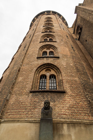 Copenhagen, Denmark, 2023 July 28, Exterior view of the Rundetaarn round tower in Copenhagen, a statue of Tycho Brahe in the foreground, verticalのeditorial素材