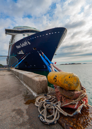 Copenhagen, Denmark, 2023 July 29, Mein Schiff 6 moored in Copenhagen, partly cloudy blue sky, in the foreground a yellow bollard and the mooring lines, verticalのeditorial素材