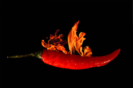 Burning red chilli pepper, black background, horizontalの写真素材
