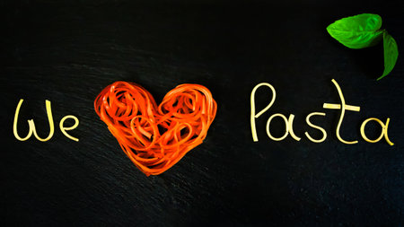 We love pasta, writing made from pasta arranged on a black slate plate, horizontalの写真素材