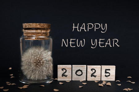 Happy New Year 2015 written on wooden cubes with dandelion on black backgroundの写真素材