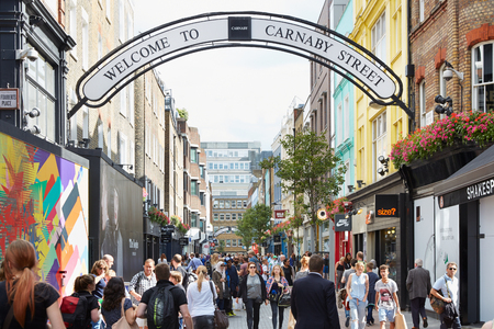 Carnaby street, famous shopping street with people in a sunny day in London