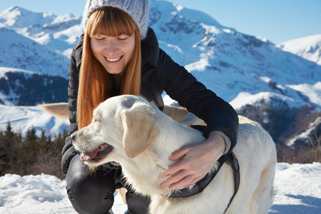 Young woman smiling hugging golden retriever pet, dog in a sunny winterの写真素材