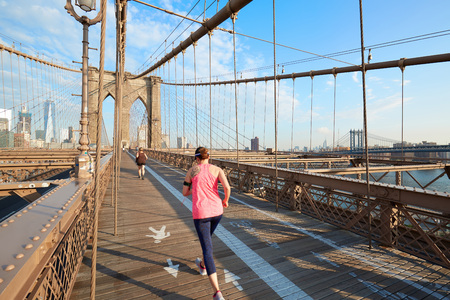 Brooklyn Bridge in a sunny morning with people running on September 8, 2016 in New York. It is an old bridge completed in 1883.のeditorial素材