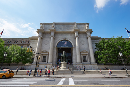 People in front of American Museum of Natural History building facade in a sunny day, blue sky on...