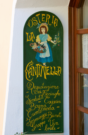 BAROLO, ITALY - AUGUST 6: Tavern Cantinella, typical italian restaurant sign in green and yellow with woman with flowers and Italian menu streets in summer day in Piedmont on August 6, 2016 in Barolo, Italy.のeditorial素材