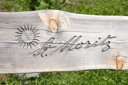 SANKT MORITZ, SWITZERLAND - AUGUST 16, 2018: City logo with sun carved in wooden bench plank in a sunny summer day in Sankt Moritz, Switzerlandのeditorial素材