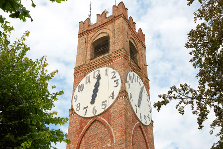 Belvedere ancient clock tower and trees in a summer day in Mondovi, Italy.の写真素材