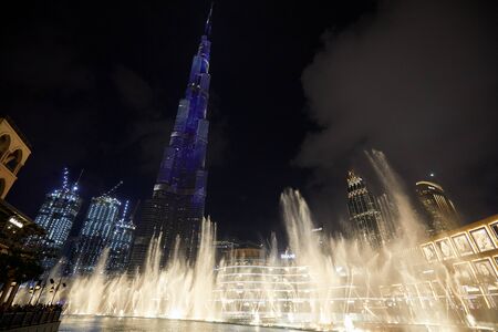 DUBAI, UNITED ARAB EMIRATES - NOVEMBER 21, 2019: Burj Khalifa skyscraper illuminated in blue and Fountain Show in front of Dubai Mall at nightのeditorial素材