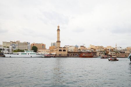Dubai creek skyline with abra and dhow traditional boats in a cloudy dayのeditorial素材