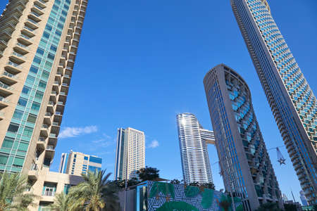 DUBAI, UNITED ARAB EMIRATES - NOVEMBER 23, 2019: Modern skyscrapers with palm trees in financial...