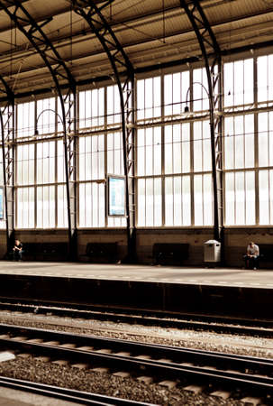 Two men far from each other at train station with stained big window behind in Harlem Hollandのeditorial素材