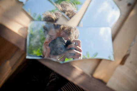 Self portrait close up with brookern mirror and reflex camera on wooden boxのeditorial素材