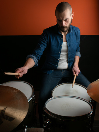 Young boy playing drum with jeans shirtの写真素材