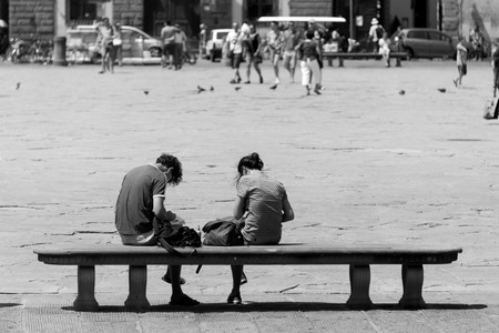 Young couple sitting in a bench in Santa Croce square, Florence, Italyのeditorial素材