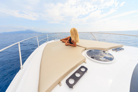 Young sexy woman lies in white dress enjoying clouds in the sky on yacht at the sea near faraglioni island capri italyの写真素材